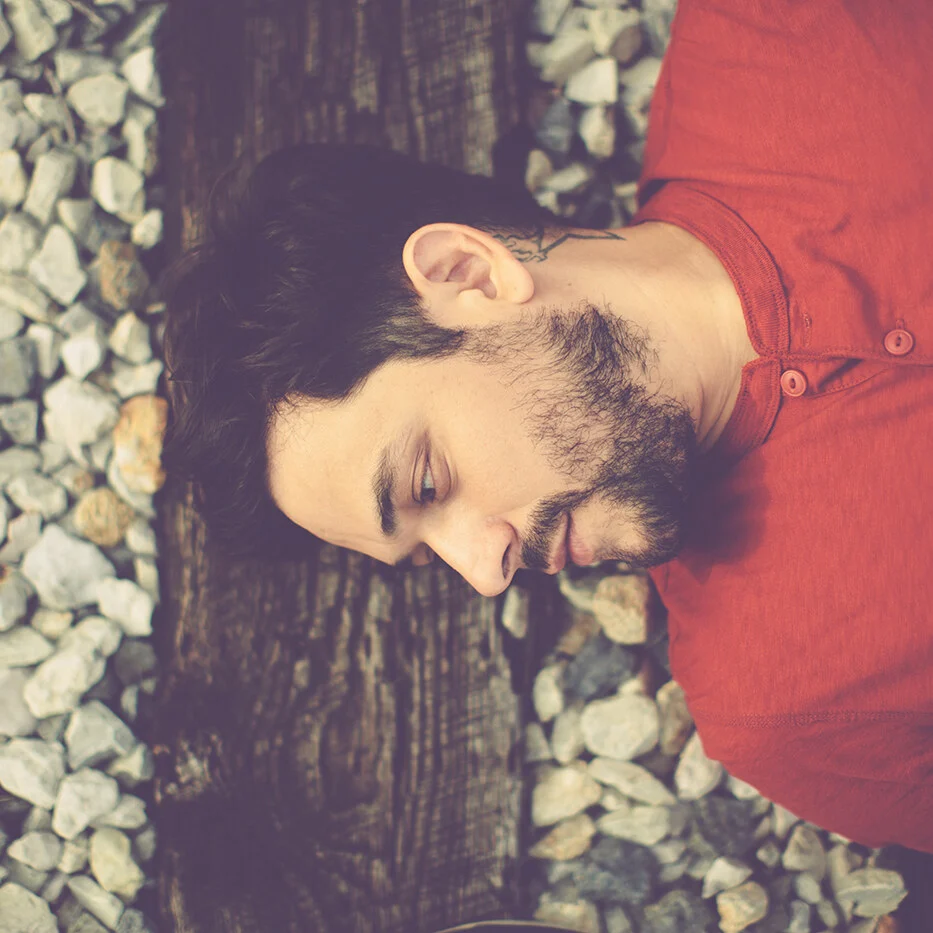 Sol Navarro lying on gravel beside a railroad tie, the Long Way Home album cover