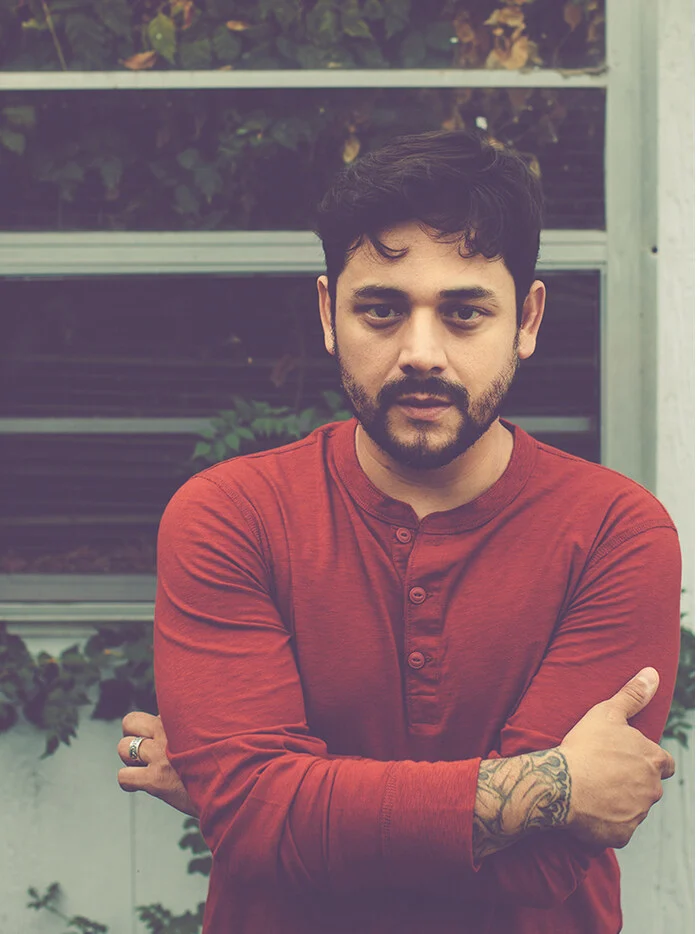 Sol Navarro in a red henley with his arms crossed